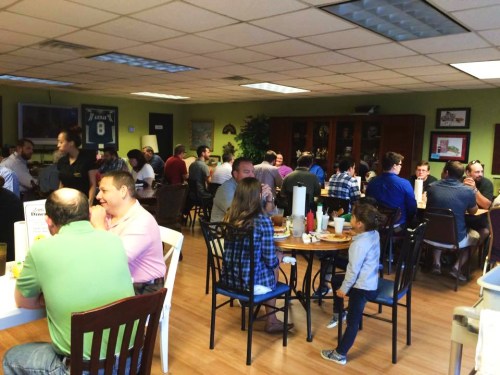 A busy restaurant interior with diners at tables, enjoying meals and socializing in a lively atmosphere.