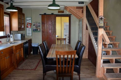 A cozy kitchen with a wooden dining table, chairs, and a staircase leading to an upper level.