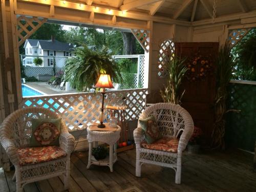 Cozy porch with wicker chairs, a lamp, and plants, overlooking a pool and garden in a serene setting.