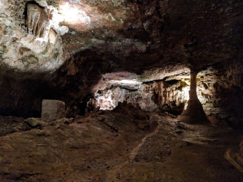 A dimly lit cave interior with rocky formations and textured surfaces, showcasing natural geological features.