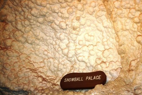 A textured cave wall with rounded formations and a wooden sign reading "SNOWBALL PALACE."