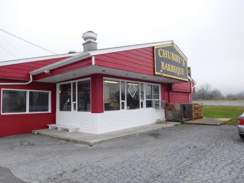 Exterior of Chubby's Barbeque, a red and white building with a sign, featuring a parking area and foggy background.