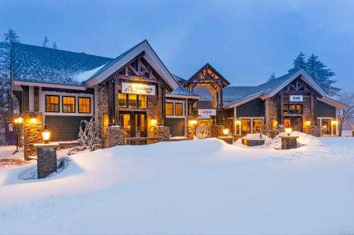 A cozy lodge with stone accents and warm lights, surrounded by snow-covered ground in a winter landscape.
