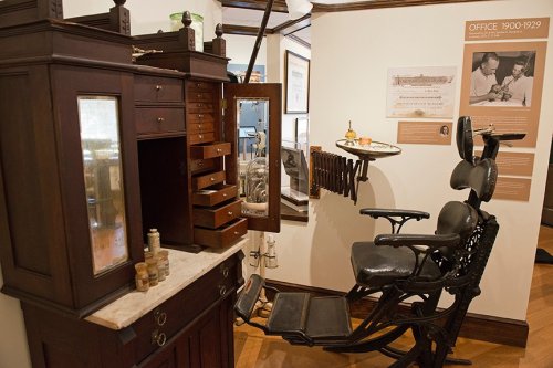 Historical dental office setup from 1900-1929, featuring a vintage dental chair and wooden cabinetry.