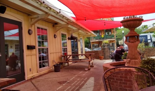 Outdoor seating area with red canopies, a fountain, and tables at a cozy café.