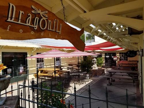 Outdoor seating area of Dragonfly Foodbar, featuring tables, umbrellas, and a charming, sunny atmosphere.