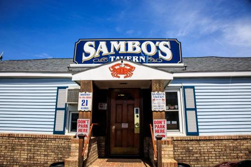 Exterior of Sambo's Tavern, featuring a blue building, a prominent sign, and a crab logo above the entrance.