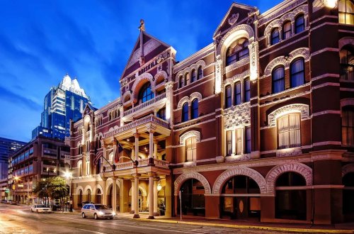 Historic building illuminated at dusk, showcasing ornate architecture against a city skyline backdrop.