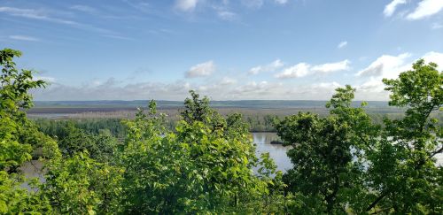 A scenic view of a river winding through lush greenery under a partly cloudy sky.