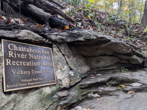 Sign for Chattahoochee River National Recreation Area, Vickery Creek Unit, mounted on a rocky surface in a wooded area.