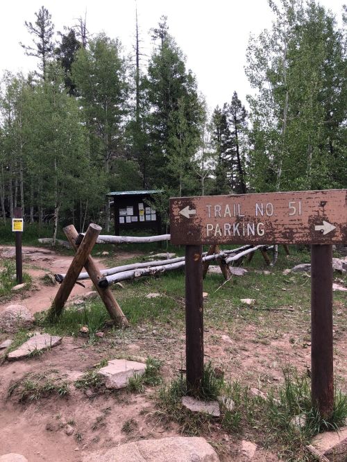 Trailhead sign for Trail No. 51 with a parking area and information board surrounded by trees and rocky terrain.