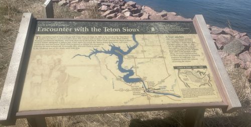 Sign detailing the history of the Pelon Sioux, with a map and information about the surrounding area near a lake.