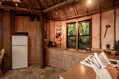 Cozy kitchen with bamboo accents, stone floor, and natural light from a window surrounded by greenery.