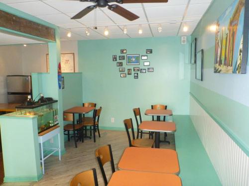 A cozy café interior with teal walls, wooden tables, and framed photos on the wall, featuring a ceiling fan.