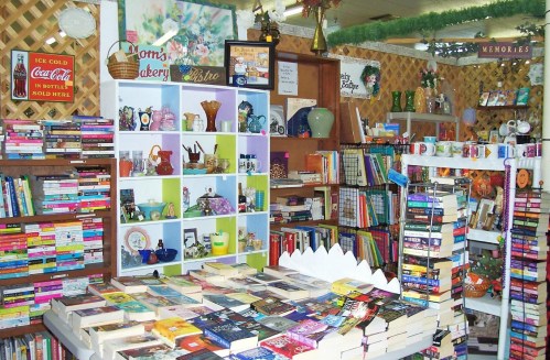 A cozy bookstore filled with colorful shelves of books, decorative items, and a table stacked with novels.