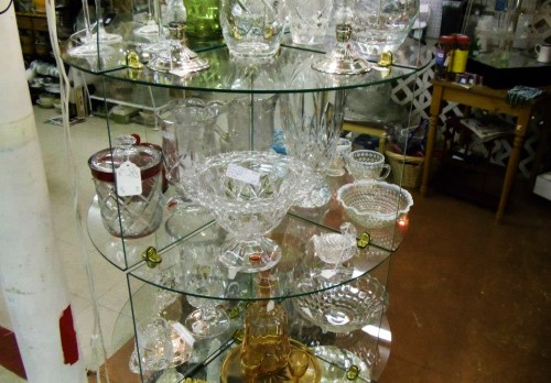 A display of various glassware, including bowls and dishes, arranged on glass shelves in a store.
