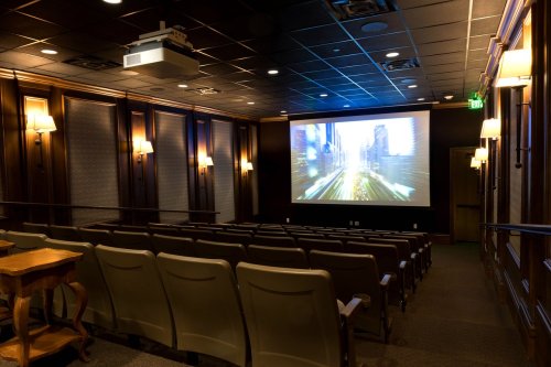 A cozy home theater with rows of seats, a large screen displaying a cityscape, and soft lighting.