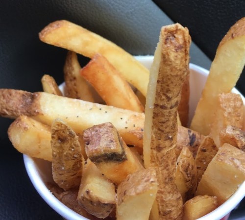 A cup filled with golden-brown French fries of various shapes and sizes.