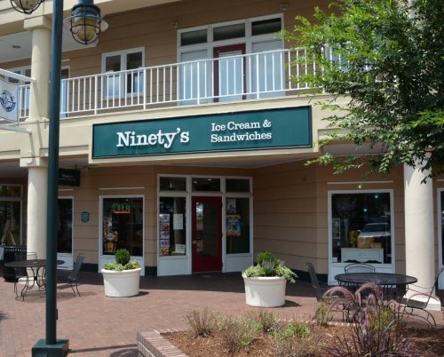 Exterior of Ninety's Ice Cream & Sandwiches shop, featuring a green sign and outdoor seating area.