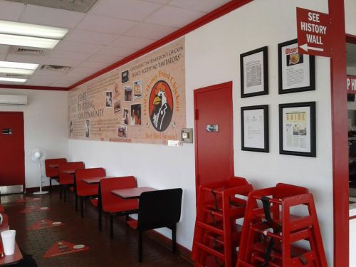 Interior of a restaurant featuring red chairs, a history wall, and a sign directing to the history wall.