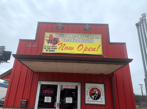 Red building with a sign reading "Hall's Honey-Fried Chicken - Best Bird Around - Now Open!" and an "Open" sign in the window.