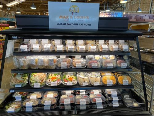 Display case filled with various packaged meals from Max & Louie's New York Diner, labeled "Classic Favorites at Home."