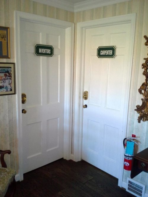 Two white doors labeled "Inventors" and "Carpenter," with a vintage decor and a fire extinguisher nearby.