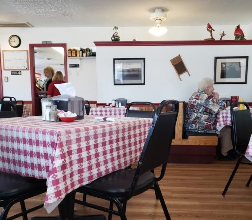 A cozy diner with checkered tablecloths, featuring a few patrons and decor on the walls, creating a warm atmosphere.