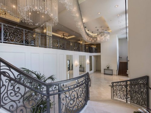 Elegant interior with a grand staircase, ornate railings, and chandeliers, creating a luxurious atmosphere.