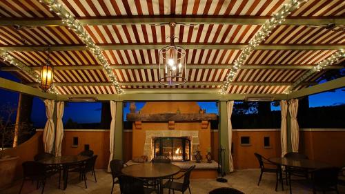 Cozy outdoor patio with striped awning, string lights, and a fireplace, set against a twilight sky.