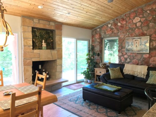 Cozy living room with stone fireplace, wooden ceiling, and a mix of modern and rustic decor.