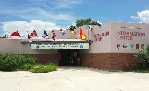 Exterior of an information center with various flags, a sign for services, and a clear blue sky in the background.