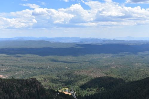 A panoramic view of lush green mountains and valleys under a blue sky with scattered clouds.