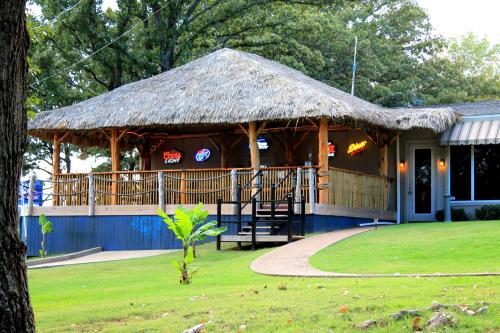 A thatched-roof pavilion with neon signs, surrounded by greenery and a pathway leading up to it.