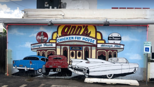 Mural of Ann's Chicken Fry House featuring classic cars and vintage soda advertisements on a blue wall.