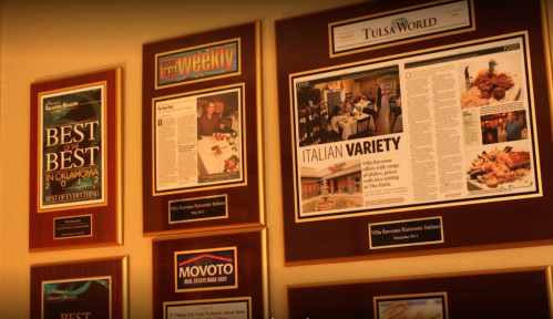 A wall display featuring various awards and articles about Villa Ravenna Restaurant, highlighting its accolades.