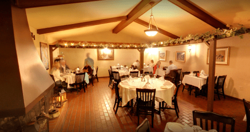 Cozy restaurant interior with tables set for dining, warm lighting, and patrons enjoying their meals.