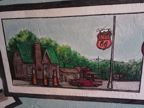 A colorful mural depicting a vintage gas station with a classic car and trees in the background.