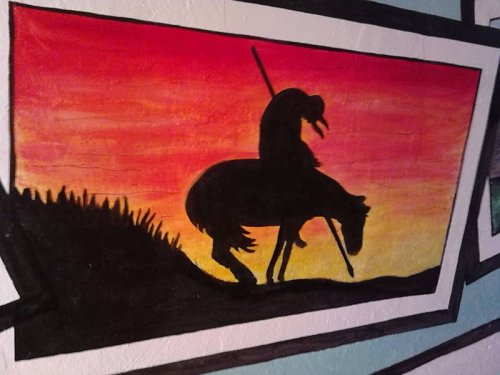 Silhouette of a rider on a horse against a vibrant sunset background with shades of orange and pink.