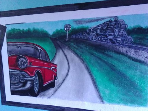 A vibrant mural featuring a classic red car and a steam train alongside a Route 66 sign on a scenic road.