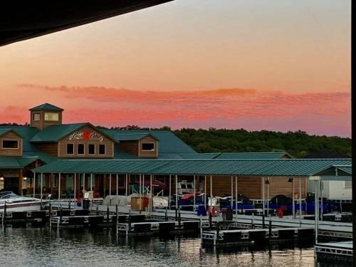 Sunset over a marina with a restaurant, boats docked, and colorful clouds in the sky.