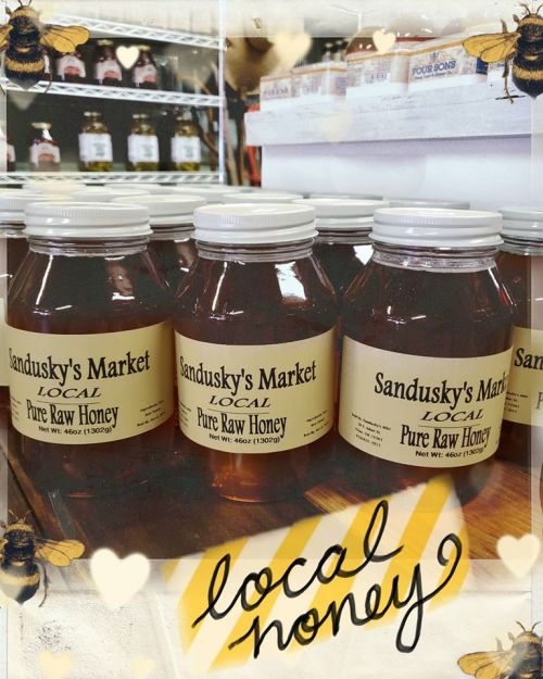 Jars of Sandusky's Market pure raw honey on a shelf, with a decorative border featuring bees and the text "local honey."