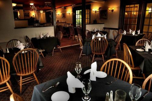 Cozy restaurant interior with wooden chairs, black tablecloths, and neatly set tables ready for dining.