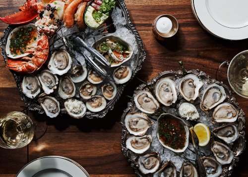 A lavish seafood platter featuring oysters, lobster, and shrimp, served on ice with garnishes and elegant tableware.