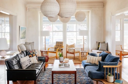 Bright living room with two sofas, a coffee table, and large woven pendant lights, featuring natural light and cozy decor.