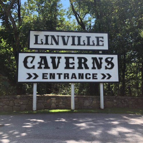 Sign for Linville Caverns entrance, surrounded by trees and blue sky.