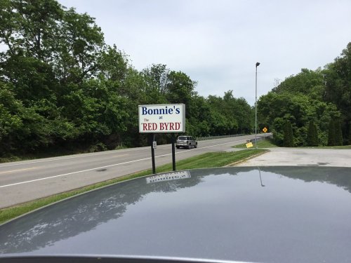 Sign for "Bonnie's at Red Byrd" along a road, with trees and a car visible in the background.