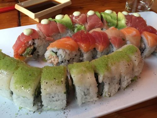 A platter of colorful sushi rolls, featuring various fish and toppings, served with soy sauce in the background.