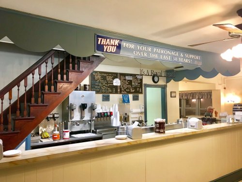 A cozy diner interior featuring a counter, menu board, and a thank you sign for 38 years of patronage.