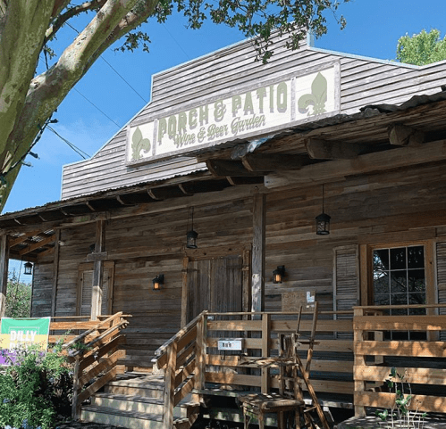 A rustic wooden building with a sign reading "Porch & Patio Wine & Beer Garden" and a welcoming entrance.
